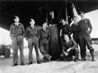 Image from the Allan Mason Forbes Alexander personal album. AMF Alexander and his No. 75 Squadron crew beside the port main wheel of their Stirling. Unknown location in England. Handwritten under the print "Operations crew 1943 75 NZ. Squadron. England. / [L-R] McDonald Rear Gunner, Des Andersen Navigator, Frank Howard Engineer, Doc Lyon Mid Upper Gunner, Tom Mayhew Wireless Operator, Phil Pullyn Bomb Aimer. A Alexander Pilot [crouching in front]."