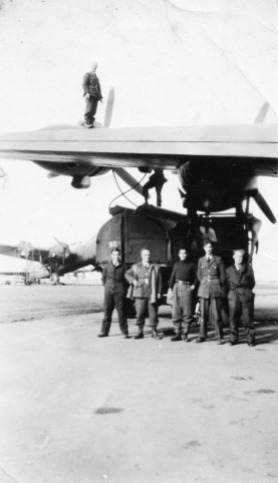 Image from the Allan Mason Forbes Alexander personal album. Informal group of RAF ground crew standing behind a fuel tanker under the wing of a No. 75 Squadron Stirling. Unknown location in England.
