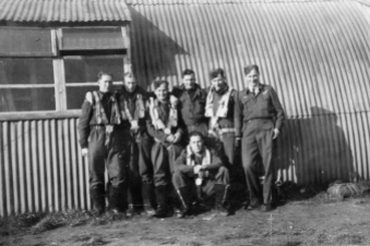 Image from the R. W. Russell personal album collection. No. 75 Squadron Lancaster crew in front of a Nissen (Quonset) hut. Believed to be at RAF Station Mepal. L-R: "Jack, Ivor, myself [R.W. Russell], George, Fred (crouching, front), Nev, Vic".